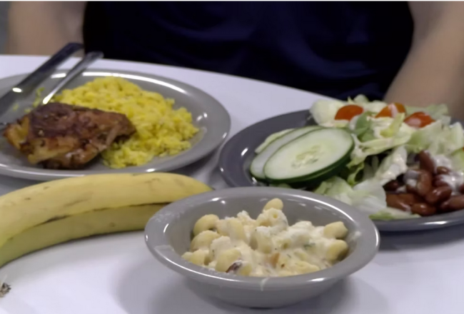 A table in the Dining Commons with plates featuring a salad, macaroni and cheese, and chicken and rice. 