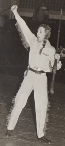 Black and white archive photo of Pioneer mascot on gym floor cheering