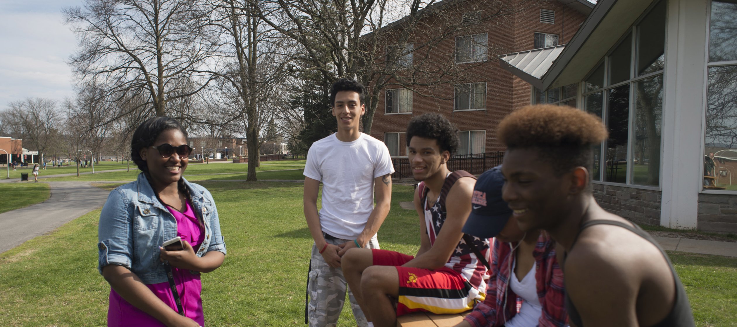 Students laughing at campus picnic tables in Spring 068
