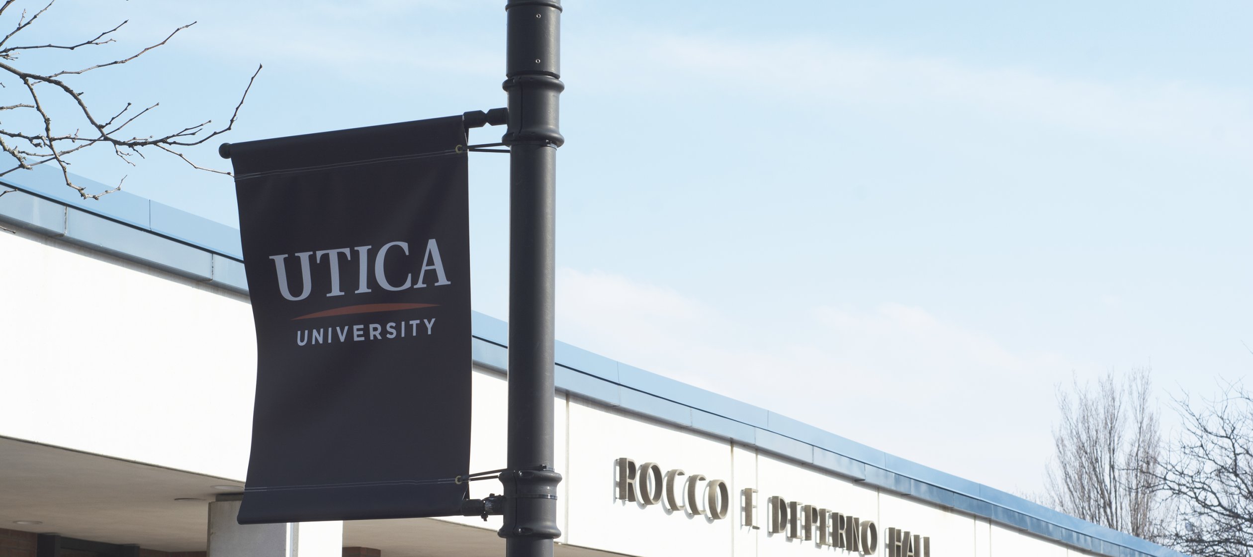 A blue Utica University banner hangs outside Rocco DePerno Hall.