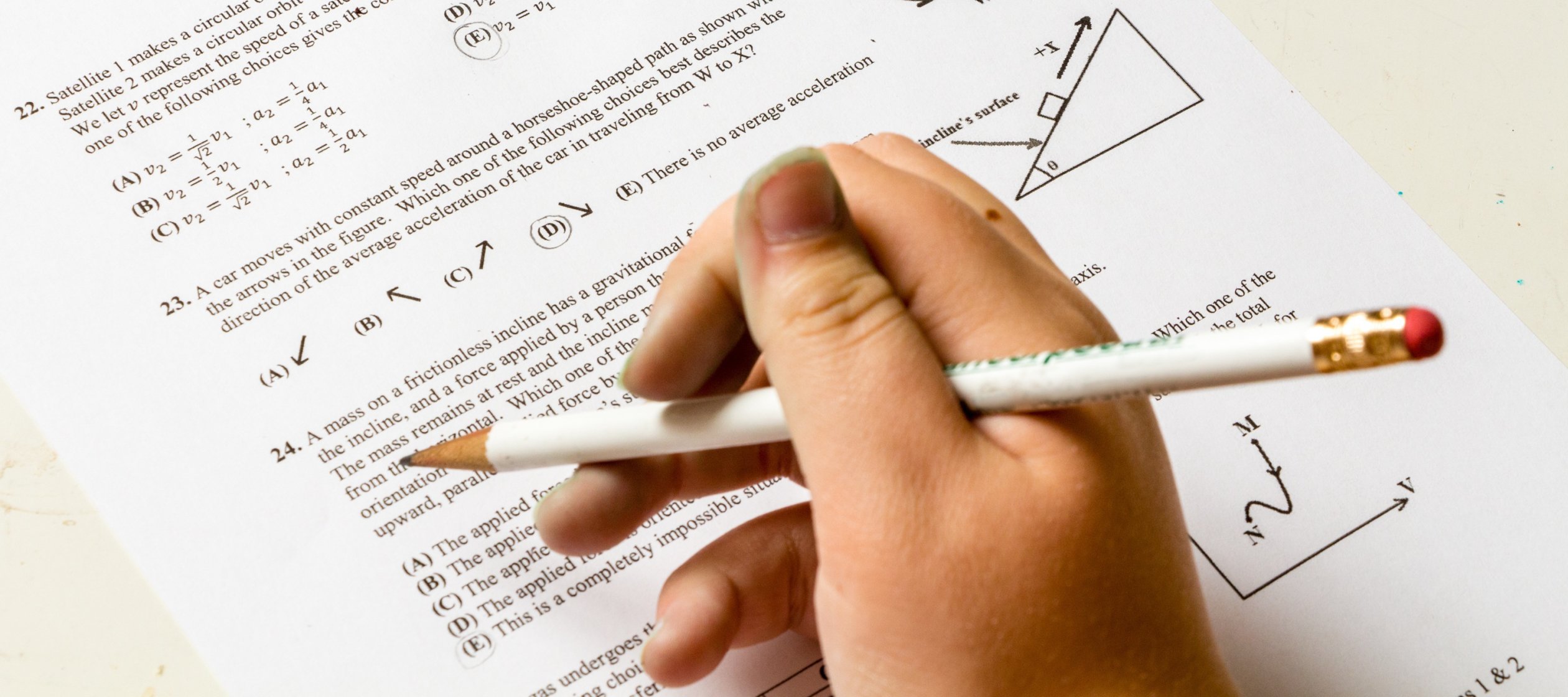 A student's hand holds a pencil over a homework worksheet of math problems.