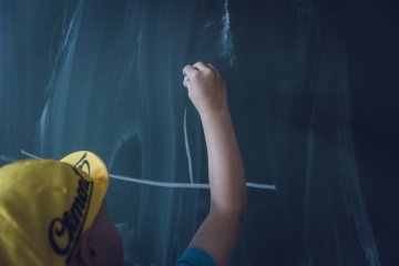 Student writing at chalkboard teaching generic
