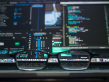 Glasses sitting on desk as data running through computers