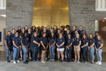 Residence Hall Staff standing by fireplace in Strebel Student Center.