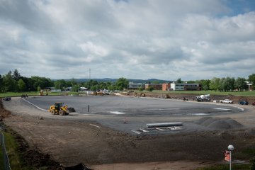 Construction vehicles move about the lot of the track and field complex.