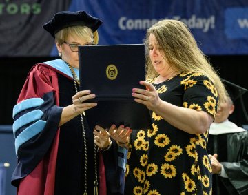 Karen Nurnberger accepts degree for her daughter, Alyssa Parrino.