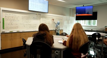 Students listen in Physics class to Professor Hava Turkakin at the board.