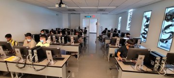 Students in the Young Scholars Program at computers in a classroom as part of a 3 week STEAM program.