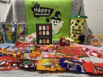 A Halloween greeting card sits amid vcarious candies, teas, coffee pods and Halloween goodies.