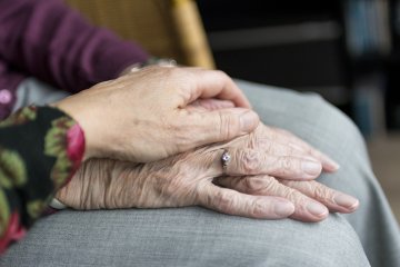 Hands of two senior citizens rest on each other.