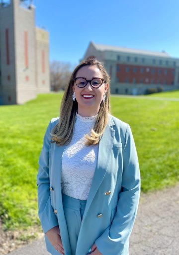 Ann Ciancia, wearing light blue jacket, stands on the Utica University campus.