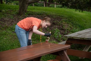 A new Utica student paints a picnic table at the 2023 Pioneer Pitch In.