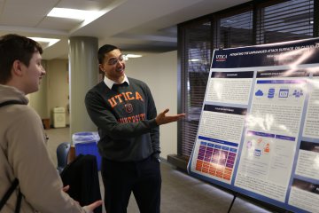 A student makes a presentation by a poster at the 2024 Student Conference for Research, Professional Activities, and Creative Arts.