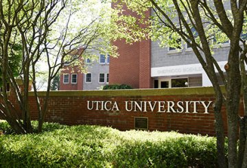 Garden wall with Utica University letters in front of a dorm