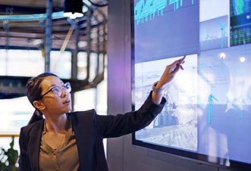 Woman pointing to large digital screen of data