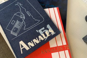 Copies of the Utica College 1951, 1972 and 1993 yearbooks stacked atop each other on a desk.