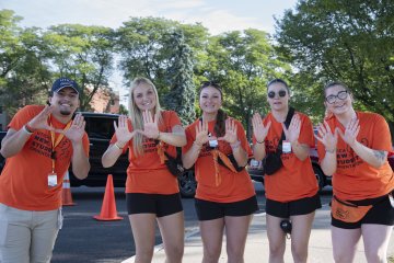 Students in orange t-shirts make moose ears with their hands.
