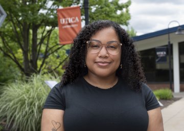 Nevaeh Scott-Dominguez stands in front of a Utica University banner on campus.