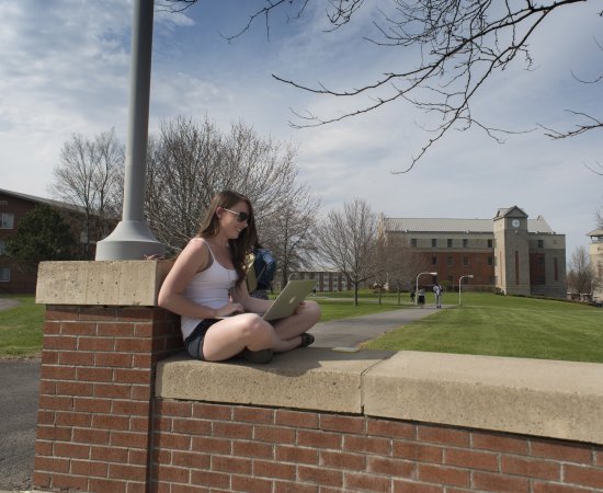 Student sitting on campus wall in Spring 060