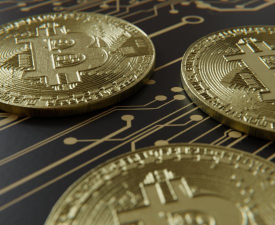 Several bitcoin representations laying on pattern of circuitry.