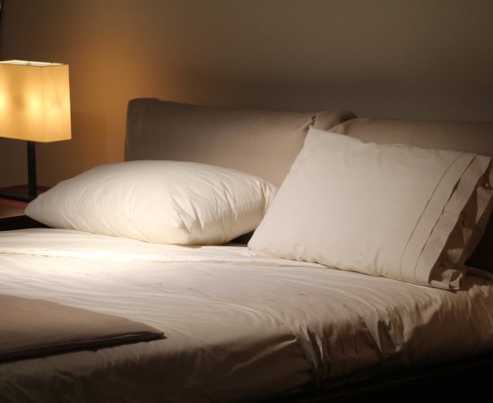 Pillows on a Bed in Dark Room with lamp light.