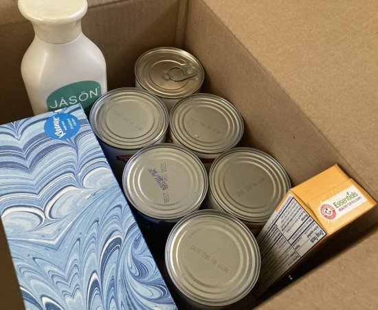 Canned goods and hygiene priducts in a cardboard box.