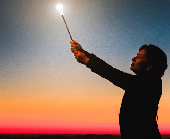 Woman holding up light into the night.