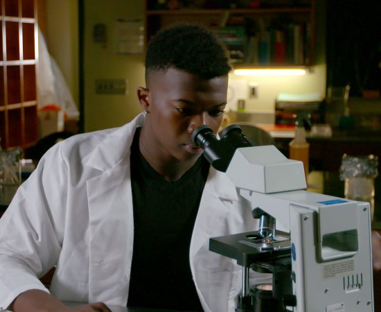 Dr Ivan Iton '21 looks through microscope
