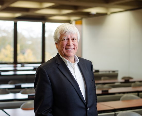 David Young Miller, Class of 1969, stands in a classroom smiling.