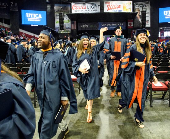 A graduate waves as members of the graduate class of 2022 exits the ceremony with their degrees.