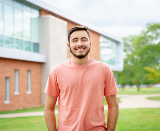Communication and Media major and Editor-in_chief of The Tangerine, Matthew Breault, stands on campus, smiling at camera.