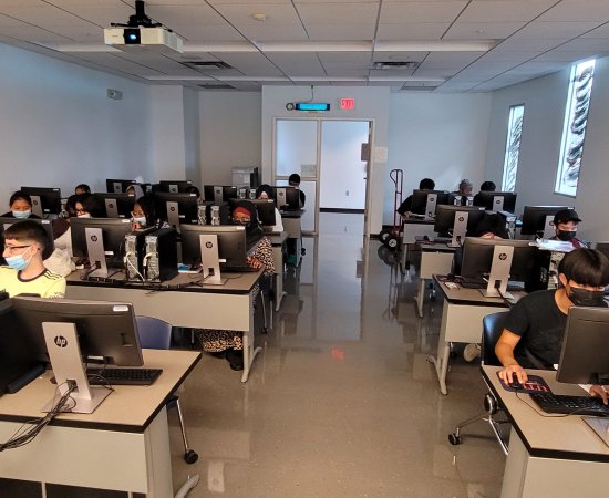 Students in the Young Scholars Program at computers in a classroom as part of a 3 week STEAM program.