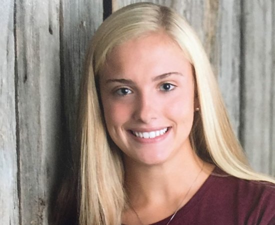 Isabelle LaBelle '23, stands in front of a wooden door, smiling.