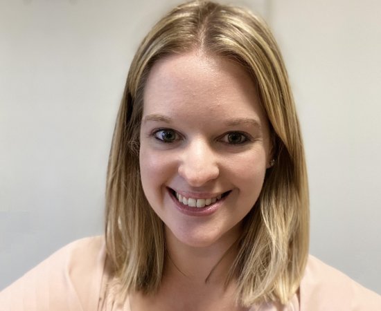 Sara Robinson, a young woman with shoulder-length blond hair, smiles at the camera in front of a beige wall.