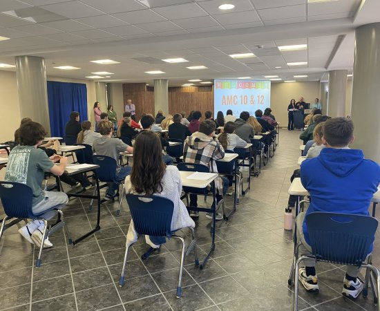 High school students sit in chairs facing a screen in the Concourse for the AMC 10 and AMC 12 Mathematics Competition.