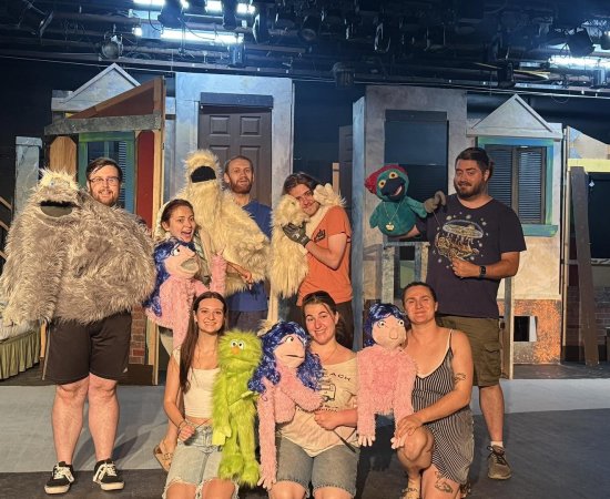 Members of the cast and their puppet companions on the stage in Strebel Auditorium for Avenue Q.