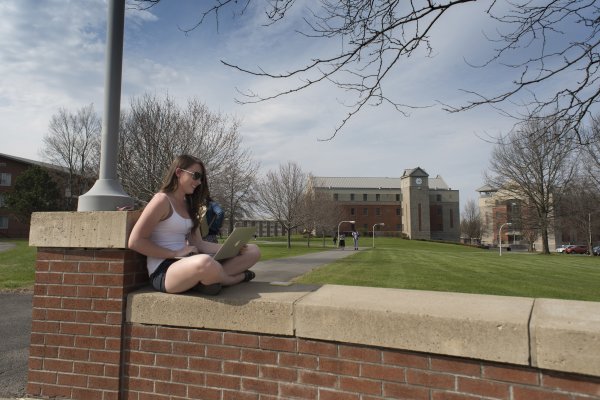 Student sitting on campus wall in Spring 060