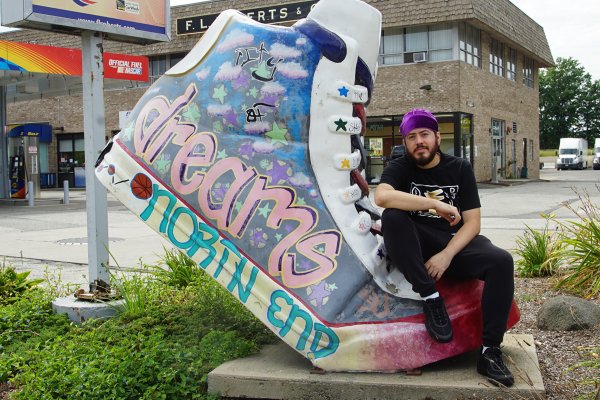 Samson Maldonado poses next to giant shoe with word "dreams" on it.