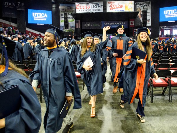A graduate waves as members of the graduate class of 2022 exits the ceremony with their degrees.
