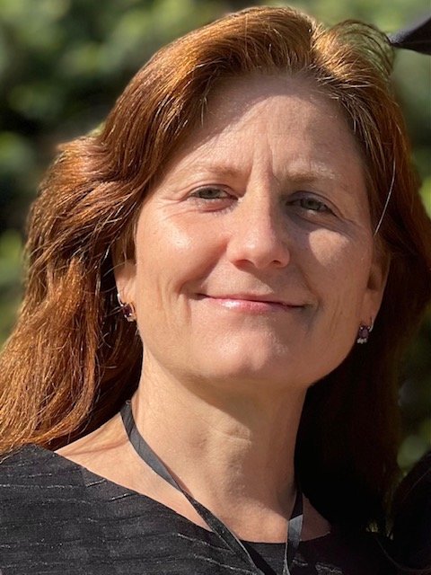 Jennifer Rioux stands outside and smiles at the camera.
