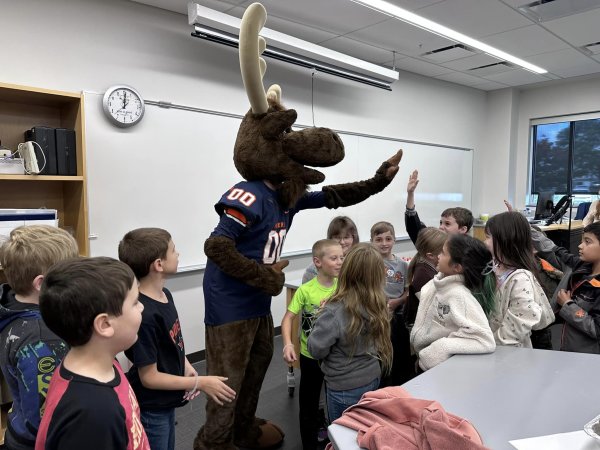 Trax the Moose high fives with elementary students from Little Falls.