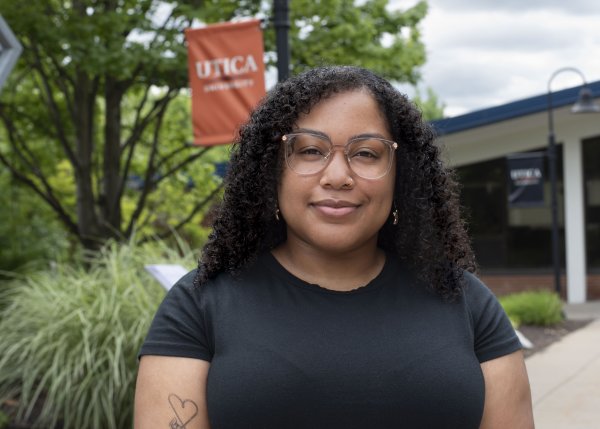 Nevaeh Scott-Dominguez stands in front of a Utica University banner on campus.