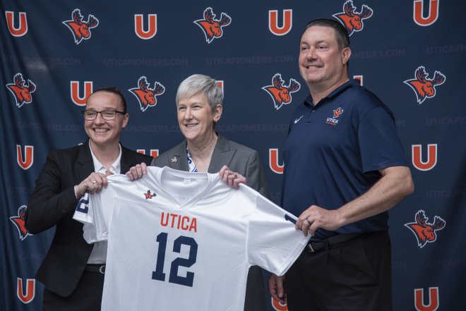Kristin St. Hilaire, Stephanie Nesbitt, and Damian Boehlert hold up a Utica Pioneers jersey.