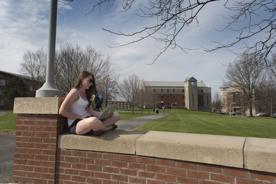 Student sitting on campus wall in Spring 060