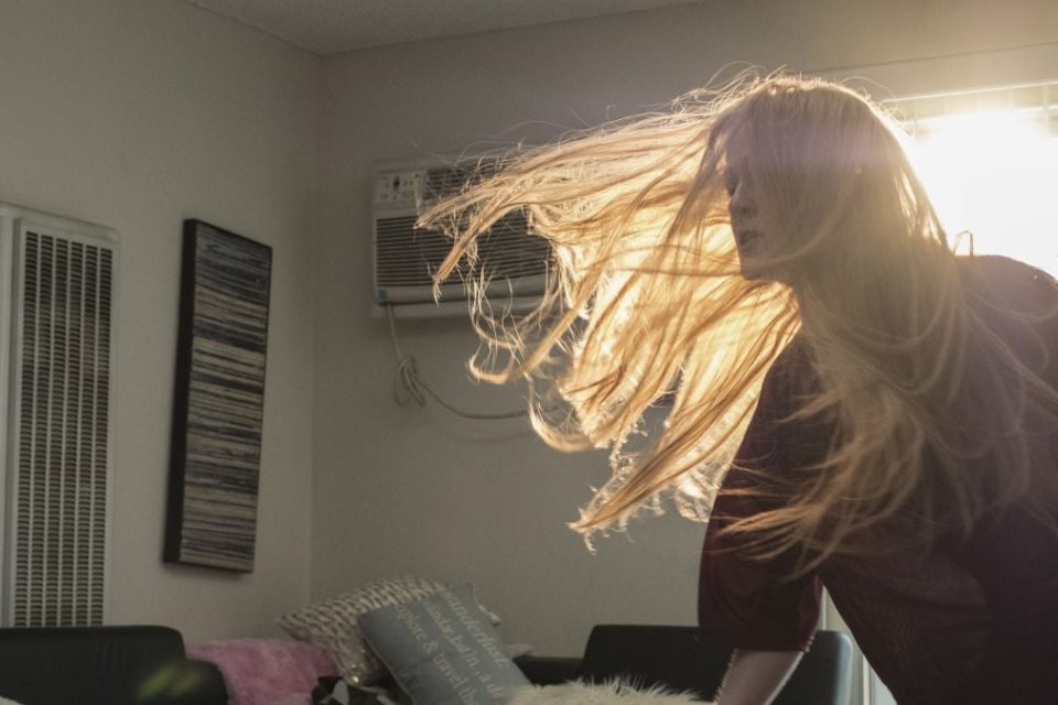 Woman tossing her hair back and forth from the film Kajillionaire.