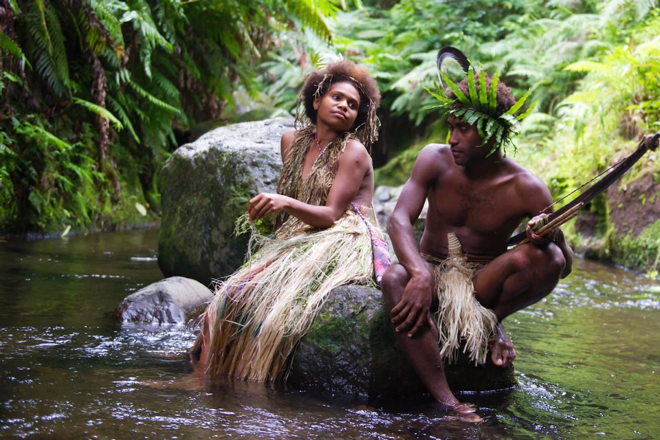 Two villagers sit on a rock amid water in the film Tanna.