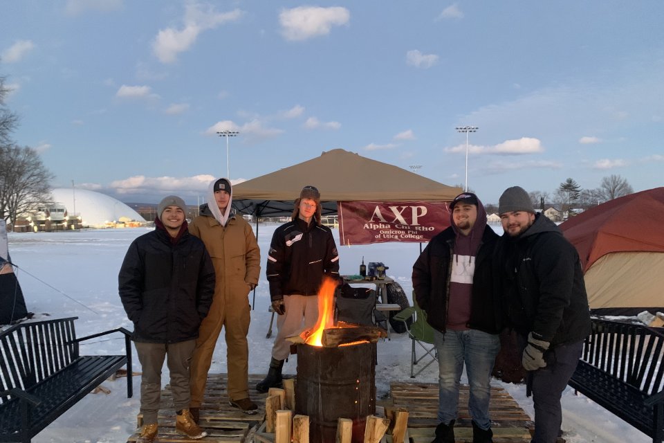 Members of AXP stand out int he cold by a fire. 