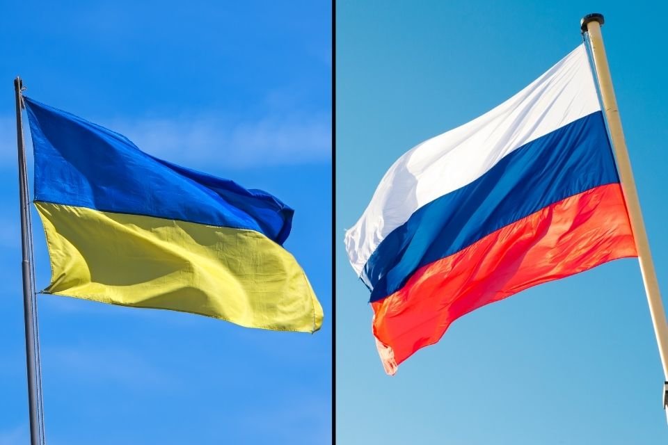 Left: The Ukrainian flag on a flagpole. Right: The Russian flag on a flagpole. They are facing head-on.
