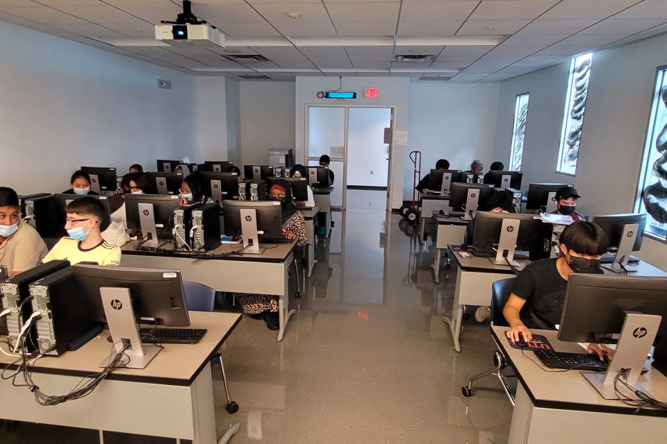 Students in the Young Scholars Program at computers in a classroom as part of a 3 week STEAM program.
