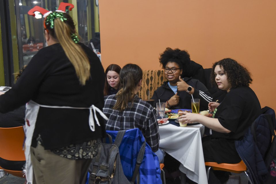 Student gives a thumbs up at the 2022 Holiday Dinner.